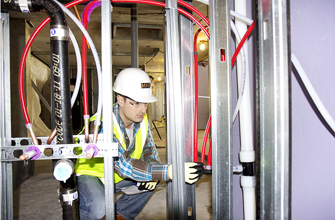 Chris Dent, MMC assistant project manager, examines the ProPEX expansion fitting connections in the Radisson Blu hotel.